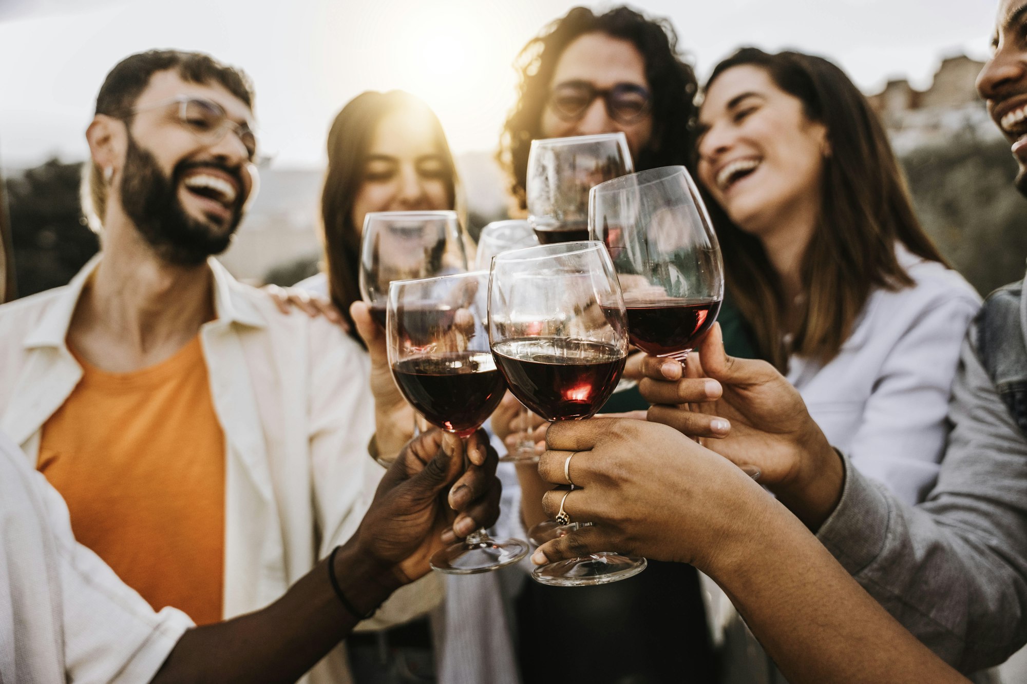 Happy friends toasting red wine glasses outside